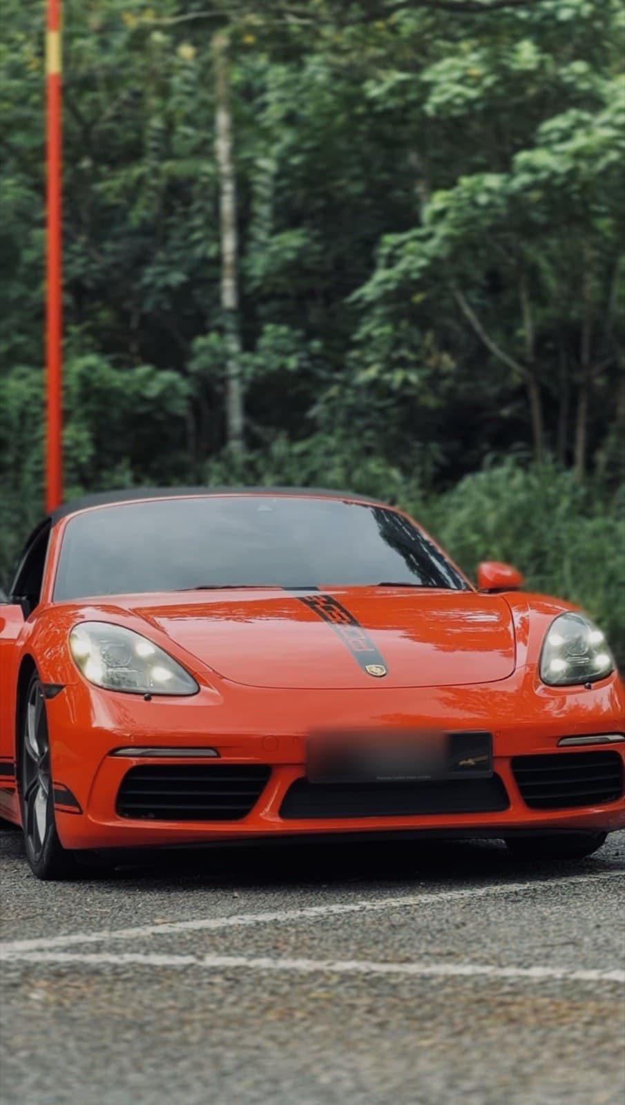 Porsche 718 Boxster on a hill road with the roof down, available for sports car hire in Kuala Lumpur
